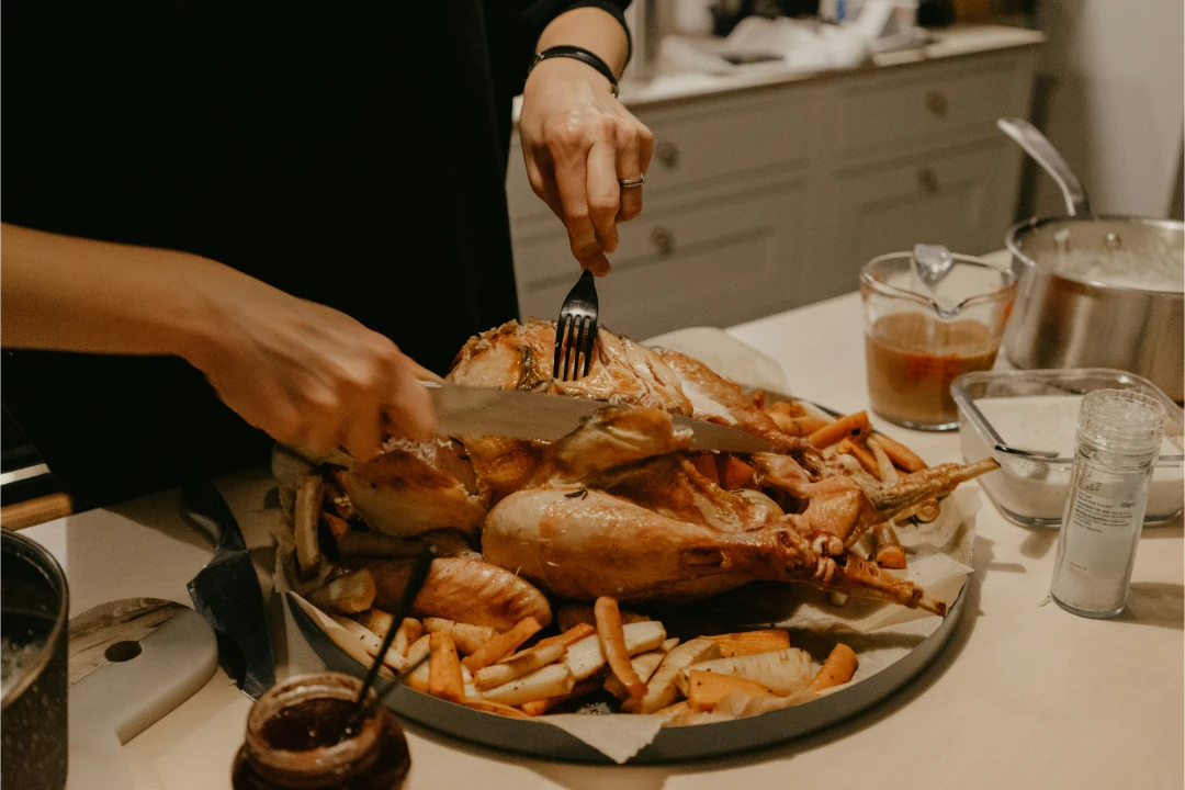 Featured image for Guide to Chicken & Turkey Time by Chef Marian. Photo of a hands carving a chicken at dinner time